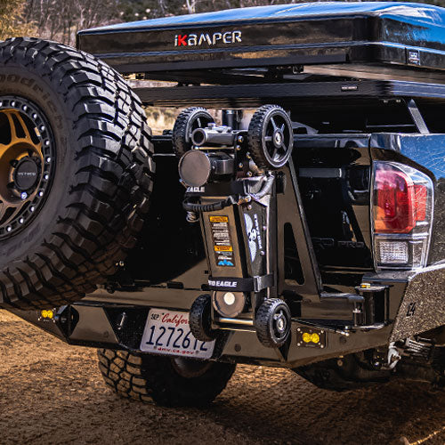 Rear view of a truck featuring a mounted "The Beast" Jack Mount 2.0 beneath a spare tire and iKamper roof top tent.