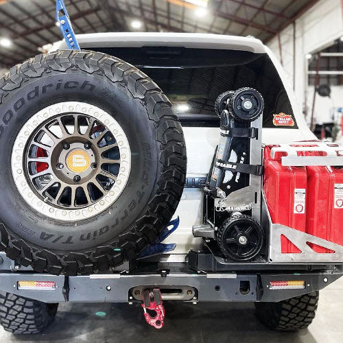 Rear view of an off-road vehicle showcasing a mounted "The Beast" 2 Ton Jack Mount 2.0 next to a spare tire.