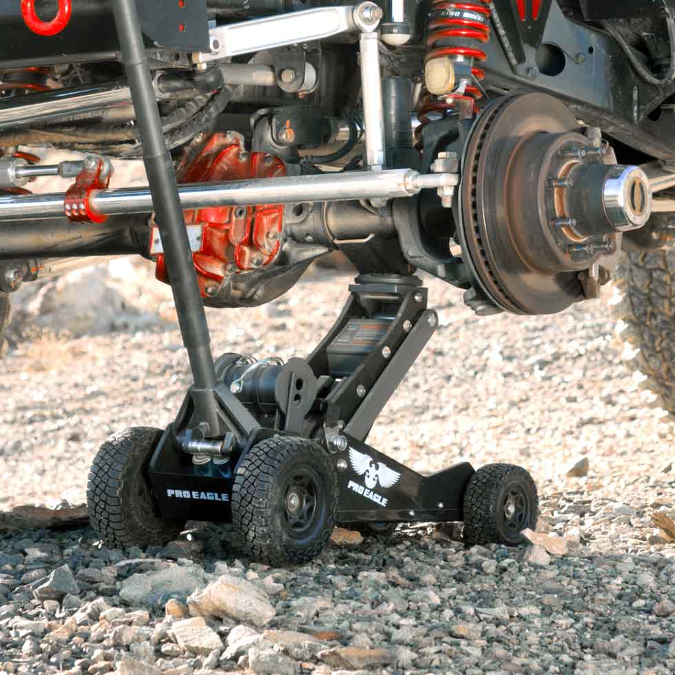 Black 3 Ton Big Wheel Off Road Jack "Kratos" positioned under a vehicle axle on a rocky surface.