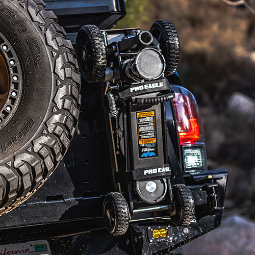 Anti-rattle strap on a mounted off-road jack on the back of a vehicle with spare tire.